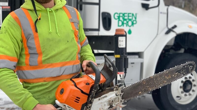 green drop worker holding a chainsaw
