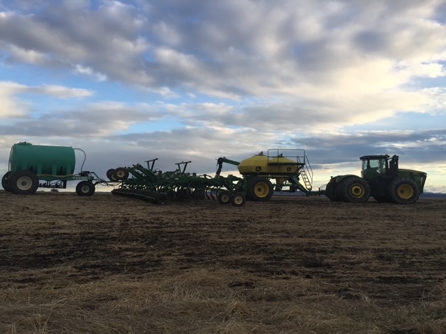 Big green tractor on a field with large equipment attached