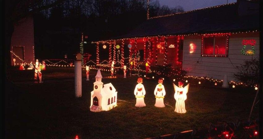 A home decorated with warm holiday lights and glowing figurines in the yard, creating a nostalgic, vintage Christmas display.