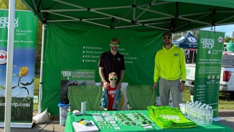 Green Drop team members welcoming visitors at their community booth during the Battle at the Beach tournament in Sylvan Lake.