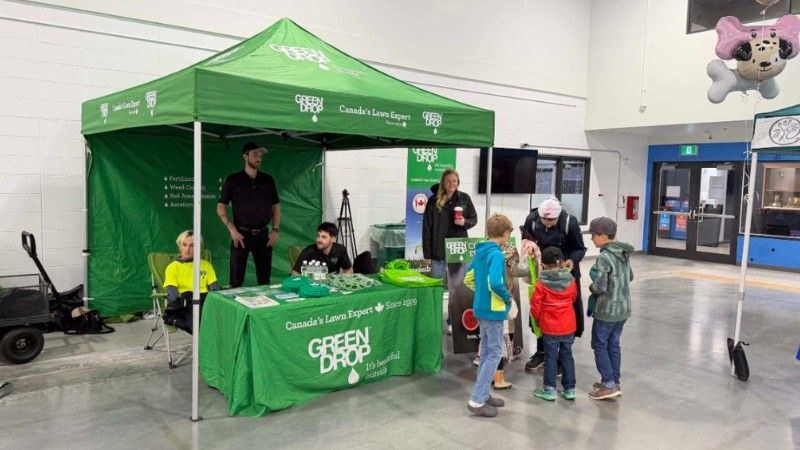 Green Drop team members welcoming families and children at the FootStock community event booth in Cochrane.