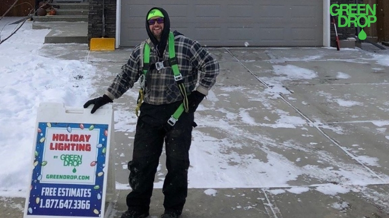 Green Drop worker holding holiday lighting sign