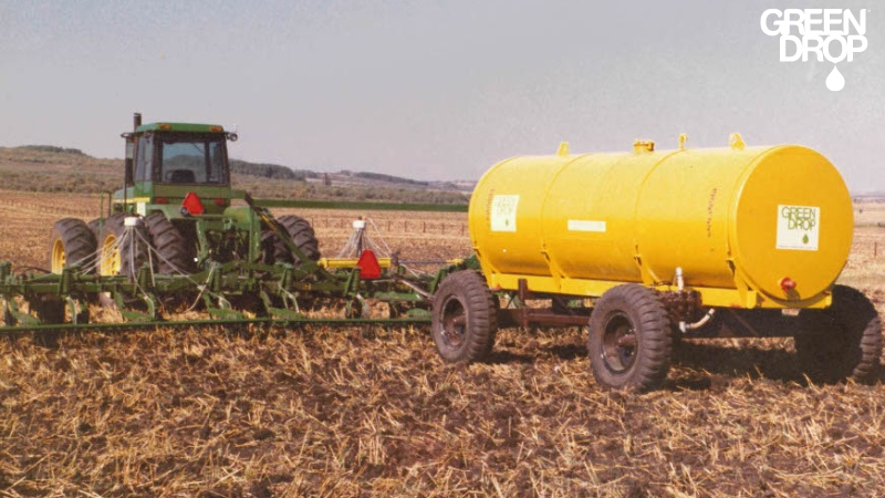 Old john deere tractor pulling a green drop fertilizer tank