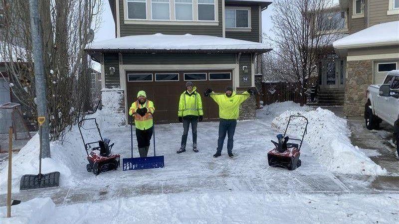 Green Drop snow removal team clearing a residential driveway with shovels and snow blowers, ensuring safe and ice-free access for homeowners.