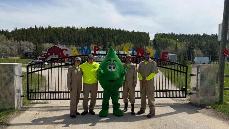 Green Drop team members and Mr. Green Drop standing at the Camp Kindle entrance in Alberta