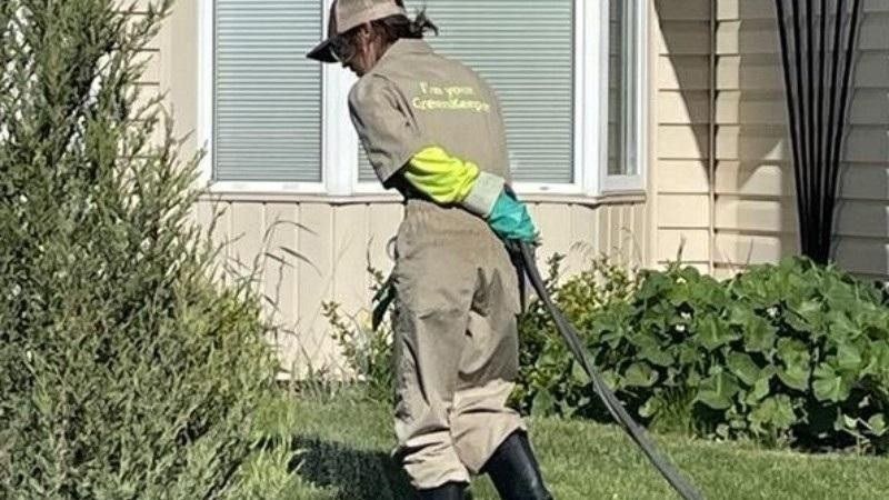 Green Drop technician performing early spring lawn care beside a home