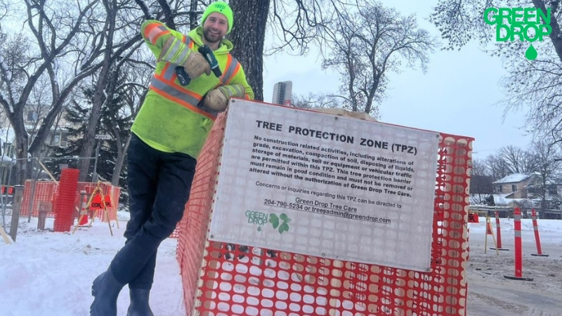 Green Drop worker standing next to a sign with snow in the back
