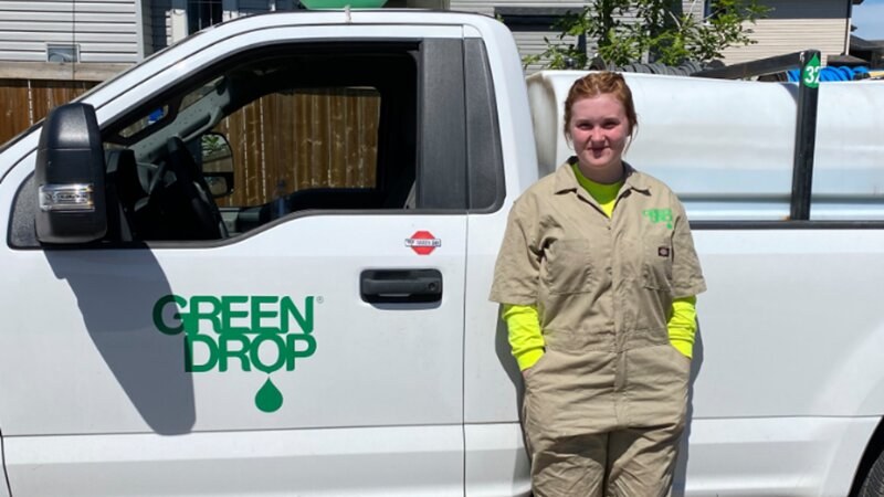 Green Drop worker leaning on a truck