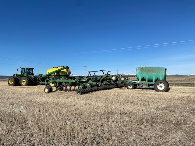 Green tractor on a field with supporting equipment