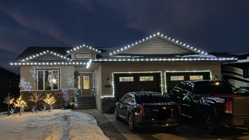 A home decorated with bright white LED holiday lights along the roofline, showing a clean and professional lighting installation.