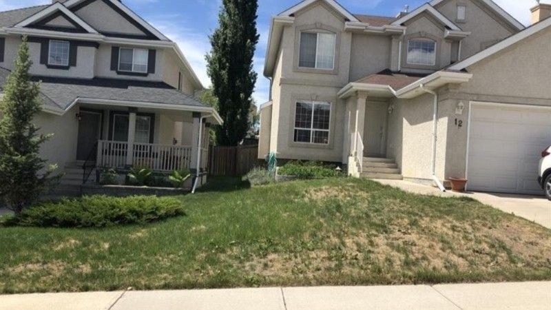 Patchy brown lawn in front of a house, showing early signs of insect or disease damage.