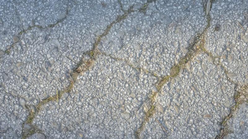 Close-up of cracked concrete caused by winter salt exposure, showing long-term damage to sidewalks and driveways.