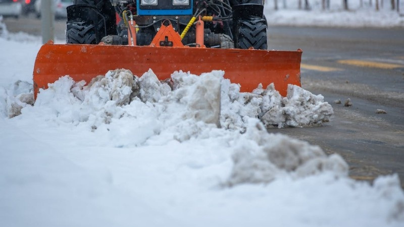 Snow plow clearing snow near a lawn edge during winter