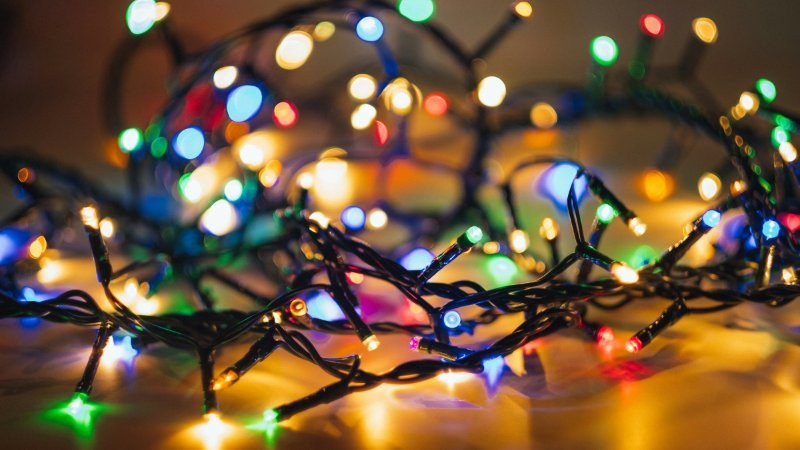 Tangled strand of multicoloured holiday lights glowing in a pile